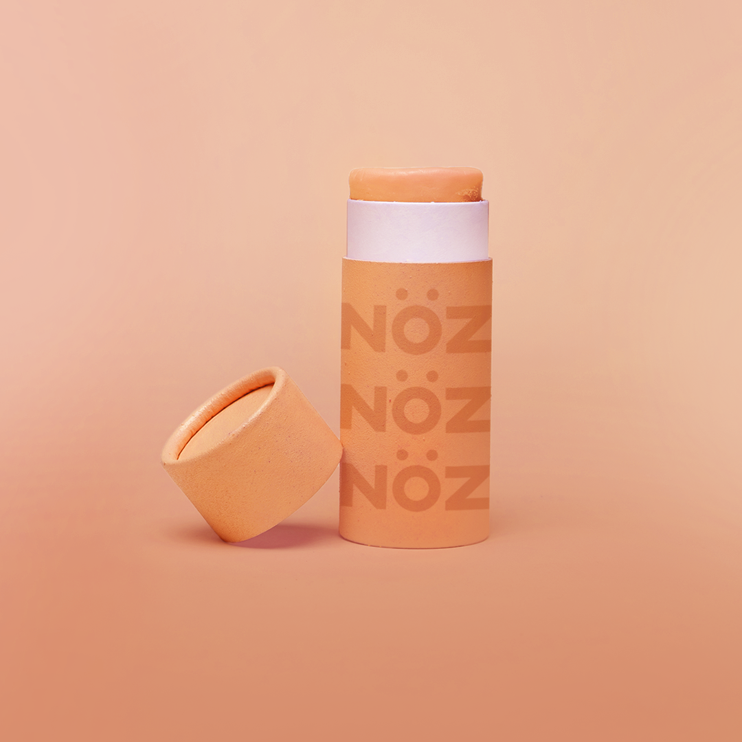 A front view of our Noz sunscreen in orange with the cap off showing some of the sunscreen stick
