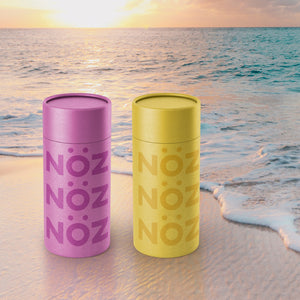 Noz sunscreen in yellow and purple on the beach keeping the reef safe